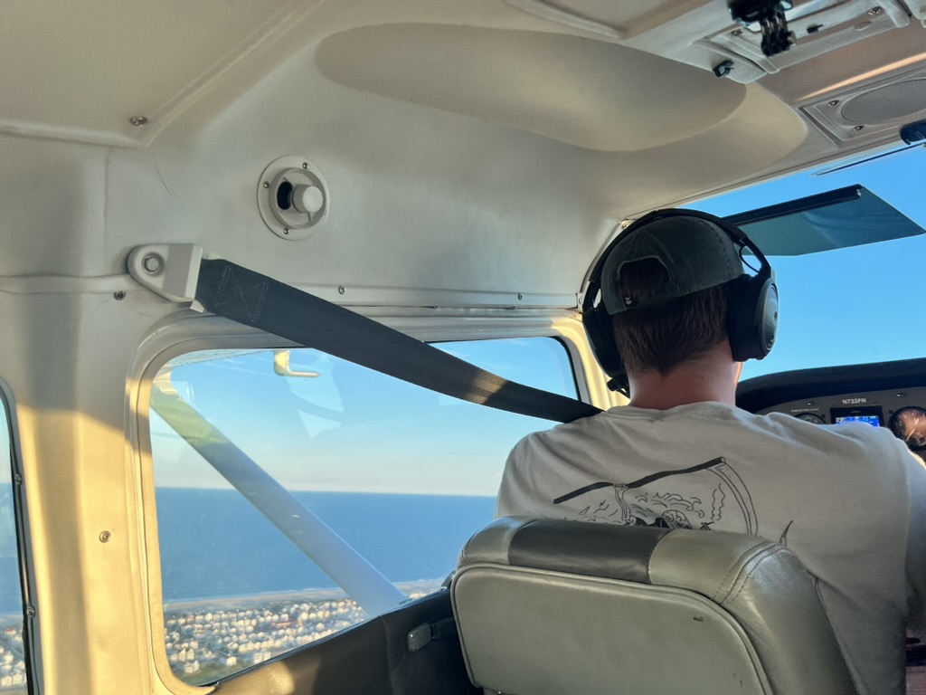 David West flying a small plane along the coast